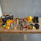 KIT Renovatievakman: metserstruweel, plakspaan, voeger, moker, beitels, handzaag, helm, bril, gehoorbescherming en veiligheidsschoenen bij een gereedschapskoffer